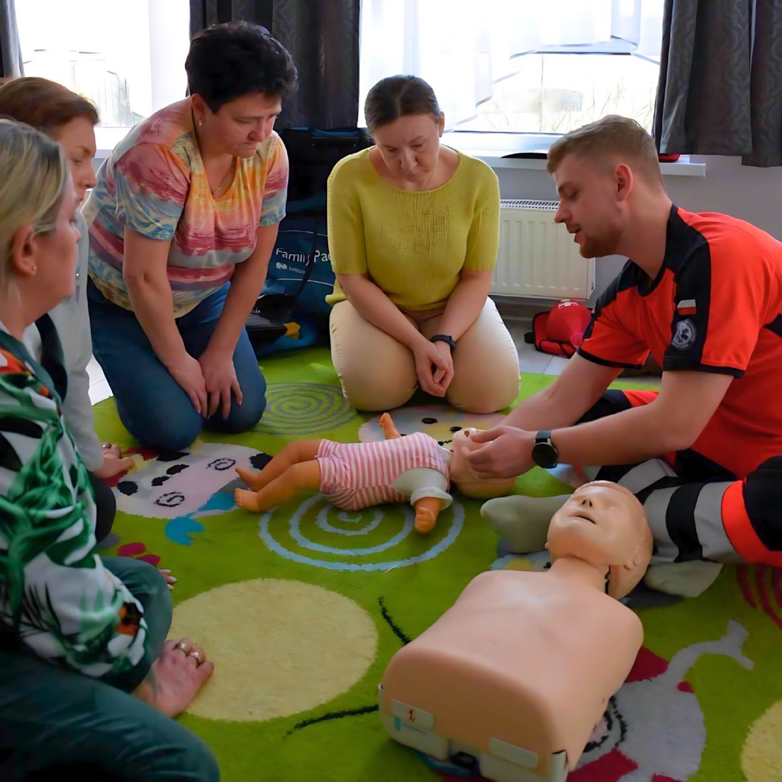 Zajęcia praktyczne — instruktor pokazuje resuscytację na fantomie niemowlęcia