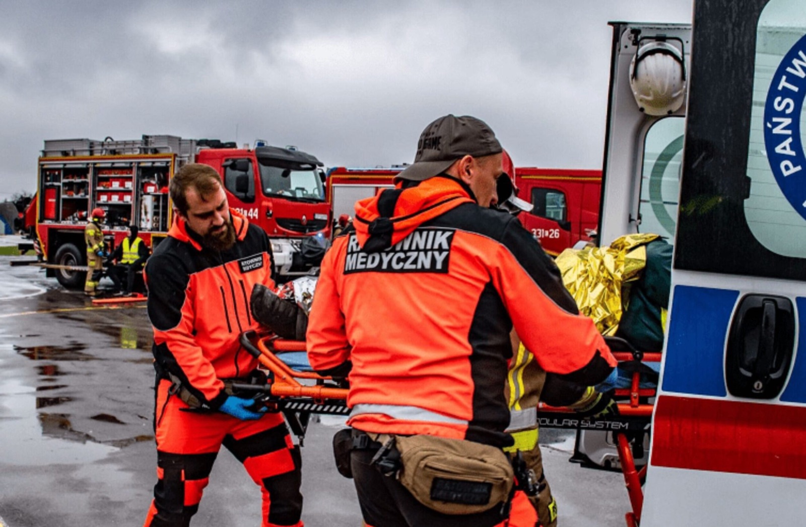 Ratownicy i strażak podczas wspólnych działań przy ambulansie